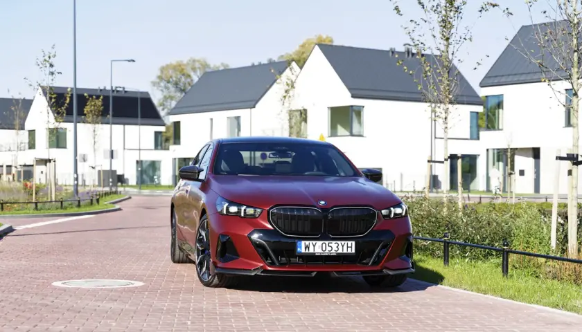 Czerwone bmw 550e na tle nowoczesnych domów.
