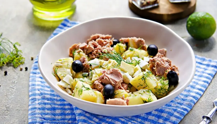 Deliziosa insalata di patate e tonno, arricchita da uova sode, olive nere e aneto fresco. Un piatto gustoso e completo.