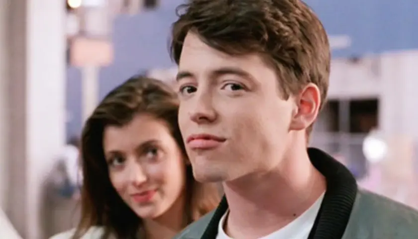 Matthew Broderick w jednym z kultowych matthew broderick filmów, uśmiecha się do kamery, podczas gdy za nim widać kobietę.
