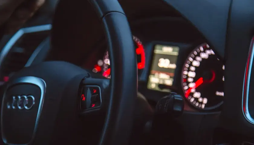 Widok na deskę rozdzielczą samochodu Audi z kierownicą i wskaźnikami.