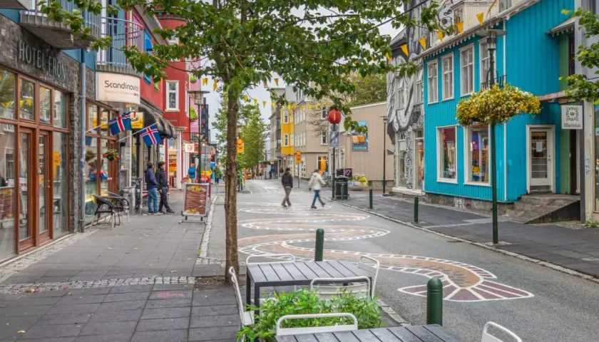 Kolorowa ulica w Reykjaviku z budynkami, flagami Islandii i artystycznymi wzorami na jezdni.