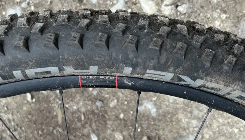 Close-up of a Schwalbe Rocket Ron tire on a mountain bike wheel, ready for a review. The tread is visible, along with rim details.