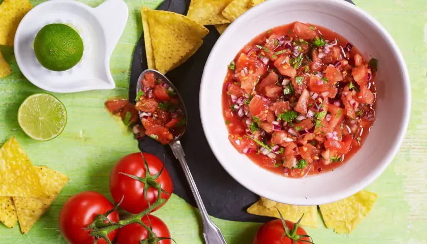 Świeża salsa pomidorowa z cebulą i kolendrą, podana z nachos i limonką. Idealna do meksykańskich potraw.