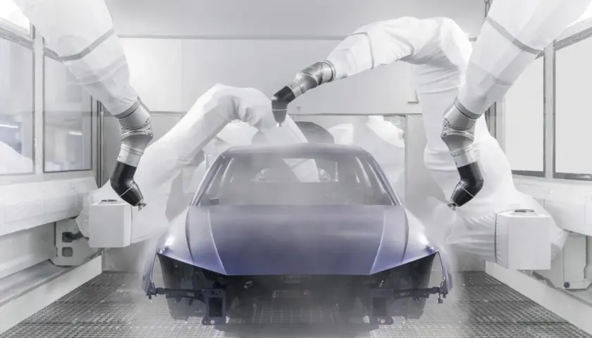 Robots pintan un coche entero en una cabina de pintura.