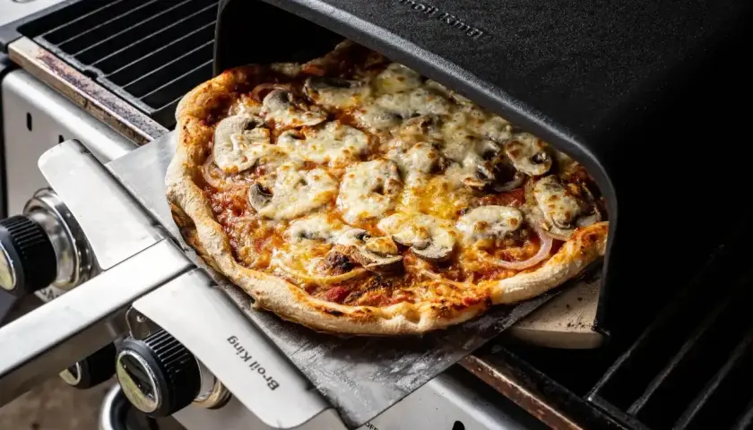 Pyszna pizza z pieczarkami i serem, właśnie wyjęta z pieca grillowego. Idealna do dzielenia się z przyjaciółmi, bo ile piec pizze, tyle radości!