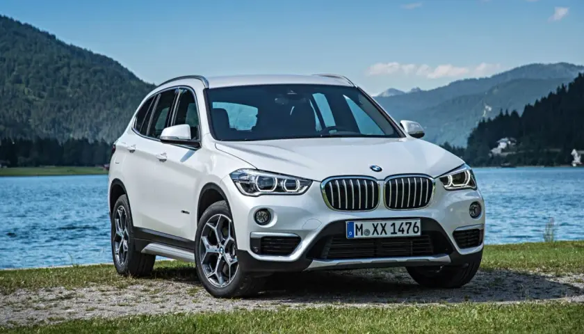 BMW X1 blanco aparcado junto a un lago. Opiniones sobre el mantenimiento de este modelo son positivas.