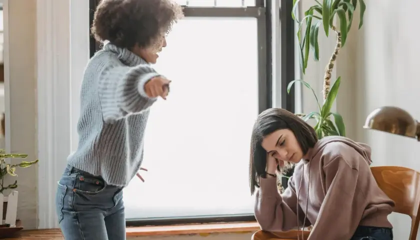 Una madre urla contro la figlia adulta, che appare abbattuta e rassegnata. Un esempio di come i genitori distruggono i figli adulti con critiche continue.