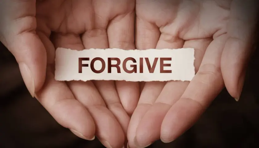 Dłonie trzymające skrawek papieru z napisem "FORGIVE". To symbol tego, co to znaczy wybaczyć – uwolnić się od urazy i otworzyć na pojednanie.
