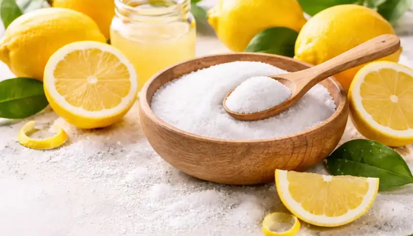 Cytryny i miska z białym proszkiem, przypominającym sól. Warto pamiętać o potencjalnej citric acid szkodliwość przy nadmiernym spożyciu.