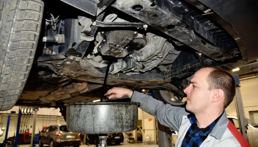 Mechanik spuszcza stary olej z samochodu. Pamiętaj o regularnej wymianie oleju w samochodzie co ile, by silnik działał sprawnie.