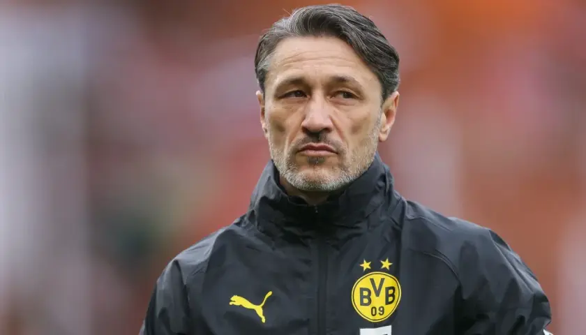 Kovac trener w czarnej kurtce z logo BVB, skupiony na boisku.
