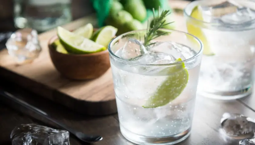 Kto pije gin z tonikiem? Orzeźwiający drink z lodem, limonką i rozmarynem, gotowy do degustacji.