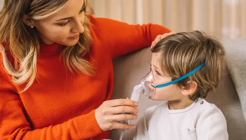 Mamma assiste il bambino con inalatore per il broncospasmo.