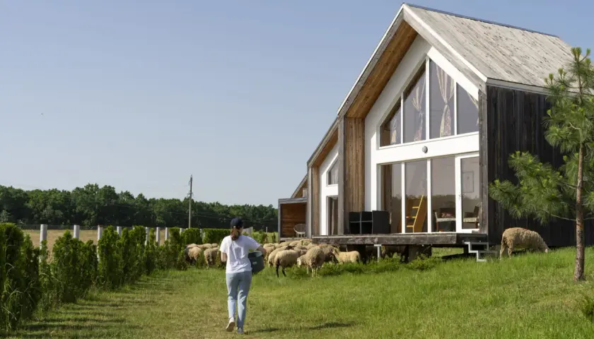 Maison ossature bois avec une femme et des moutons. Le schéma de fondation est invisible.