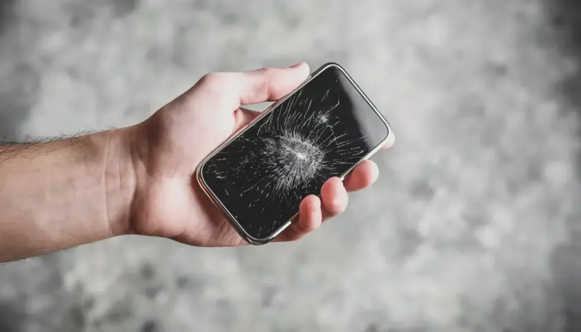 Dłoń trzyma pęknięty telefon. Zastanawiasz się, ile trwa wymiana szybki w telefonie?