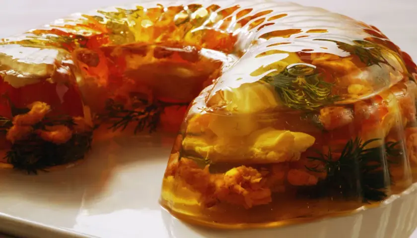 Wykwintny filet z karpia w galarecie, z dodatkiem ziół i warzyw, prezentuje się apetycznie.