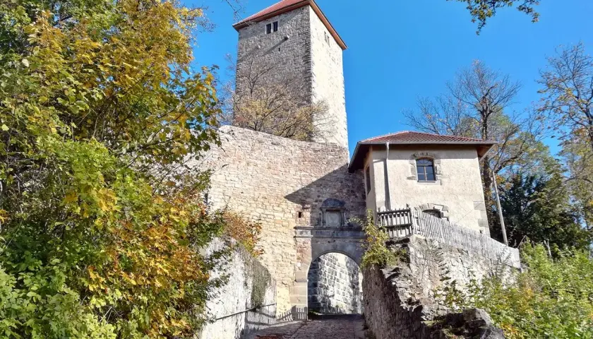 Herbstliche Bäume umgeben die **Ruine Lichtenburg** mit ihrem markanten Turm und Torbogen.