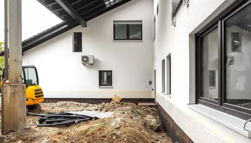 Baustelle am Altbau: Ein Bagger und Rohre liegen im Erdreich. Der Kellerbereich ist freigelegt, was bei solchen Arbeiten normal ist.