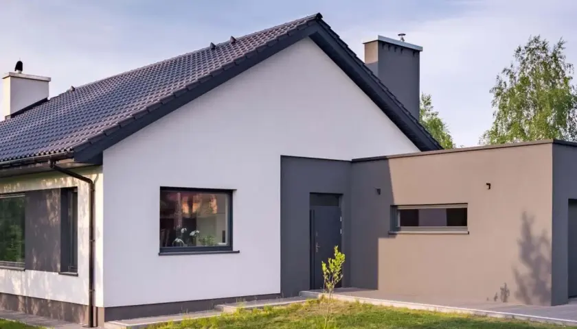 Nowoczesny dom z białym i grafitowym tynkiem. Elewacja z prostymi liniami i dużymi oknami.