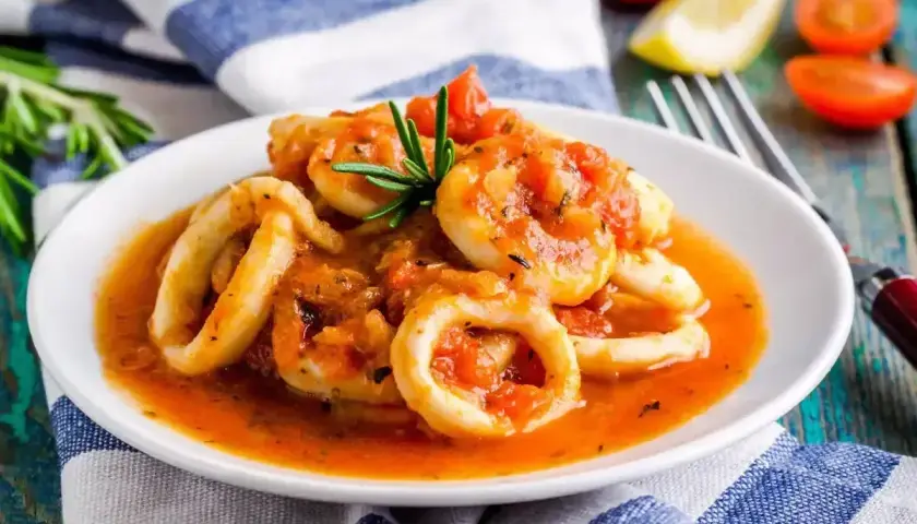 Anelli di calamari in umido con pomodoro e rosmarino, un piatto saporito e invitante.