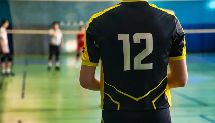 Męski strój siatkarski z numerem 12 na plecach. Zawodnik gotowy do gry na boisku.