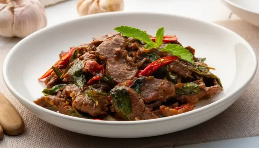 Aksamitne kawałki wołowiny z bazylią i papryczką chili, aromatyczne wołowina po tajsku, podane w białej misce.