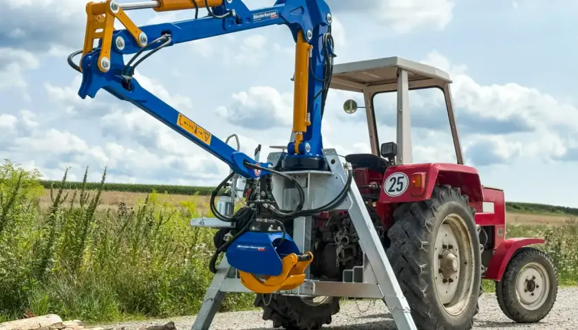 Ein blauer Binderberger 3-Punkt-Kran für Traktoren, gebraucht, mit Greifer, bereit für den Holzeinsatz.