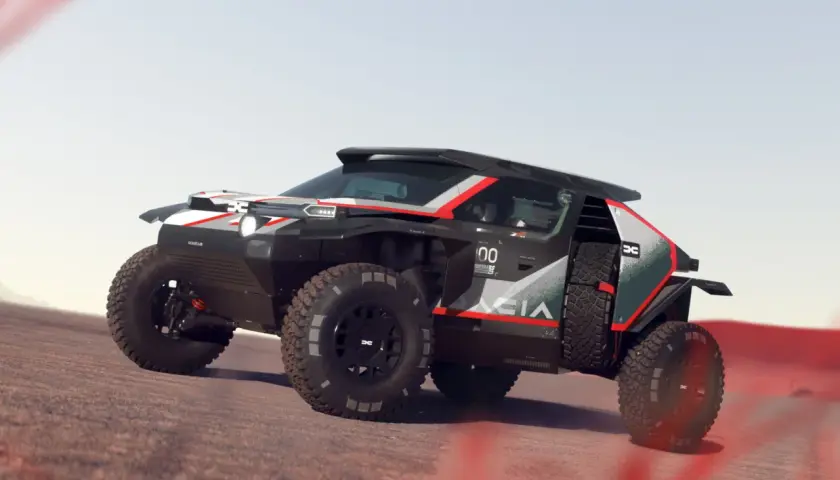 Un Dacia Sandrider nero e rosso sfreccia su un terreno sabbioso, pronto per l'avventura nel deserto.