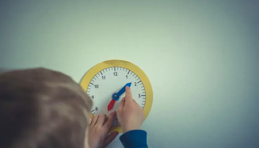 Dziecko uczy się odczytywać godzinę na zabawkarskim zegarze. Prosta nauka zegara to świetna zabawa!