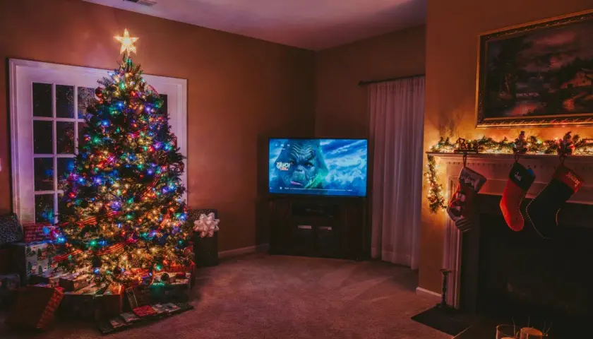 Albero di Natale illuminato, regali sotto, e il Grinch in TV. Perfetto per ascoltare canzoni di Natale in inglese testo.