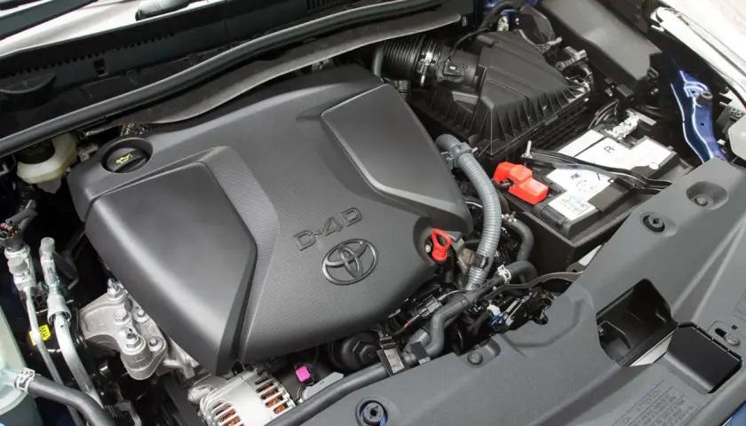 Silnik D-4D w Toyota Avensis T27. Widoczny jest czarny plastikowy dekiel silnika z logo Toyoty i napisem D-4D, akumulator oraz elementy układu dolotowego.