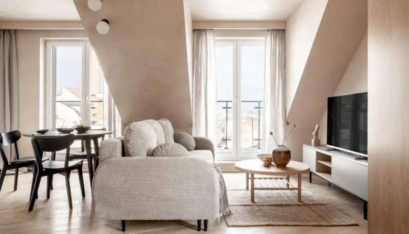 Przytulny salon z sofą, stolikiem kawowym i jadalnią. Zastanawiasz się, ile średnio kosztuje kawalerka w Krakowie?
