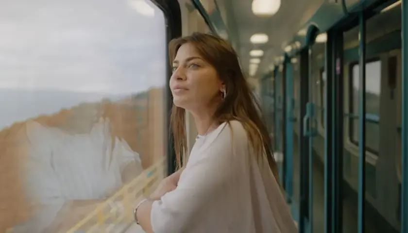 En ung kvinna tittar ut genom tågfönstret, drömmande om sin interrail resa.