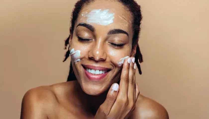 Une femme applique une crème sur son visage, une étape essentielle de sa routine de protection contre le soleil.