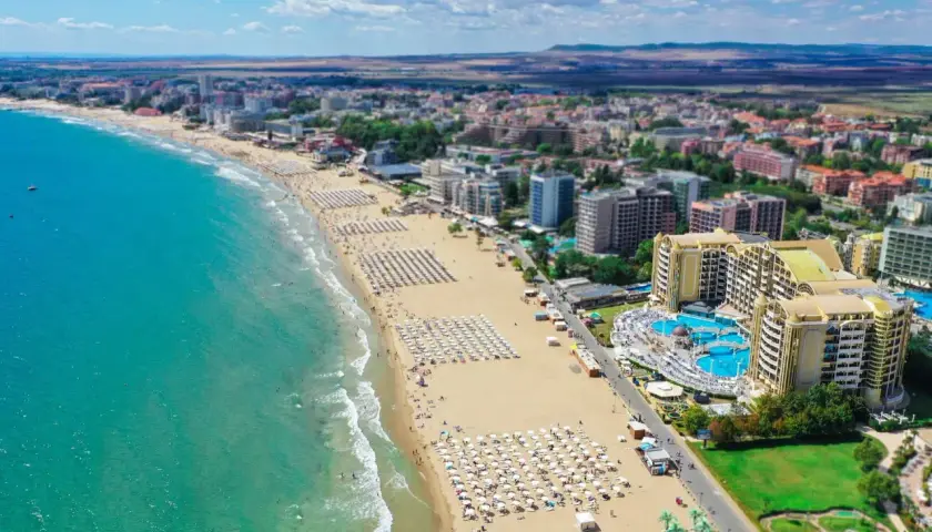 Słoneczny Brzeg, Bułgaria: rozległa plaża z białymi parasolami, turkusowe morze i luksusowy hotel z basenami.