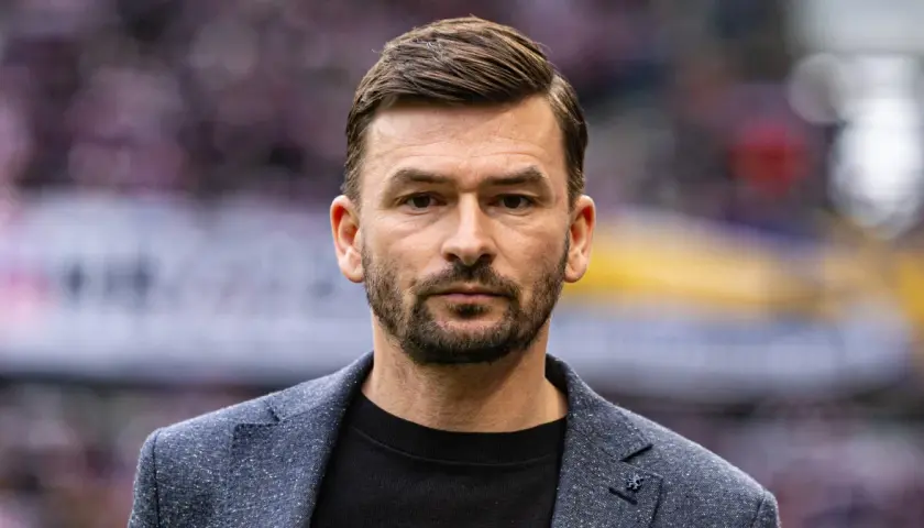 Górnik Zabrze trener, w eleganckim garniturze, patrzy prosto w obiektyw.