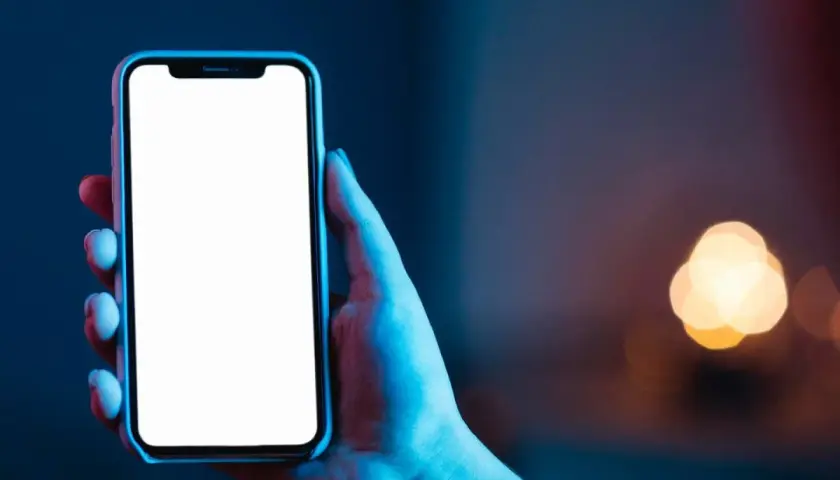 Dłoń trzyma smartfon z pustym ekranem **AMOLED**, otoczony niebieskim i czerwonym światłem.