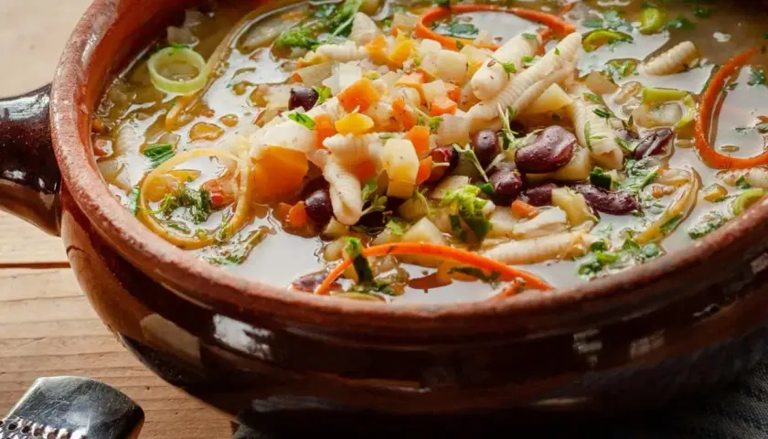 Herzhaftes Minestrone Rezept in einer rustikalen Tonschüssel, gefüllt mit Gemüse, Bohnen und Nudeln.