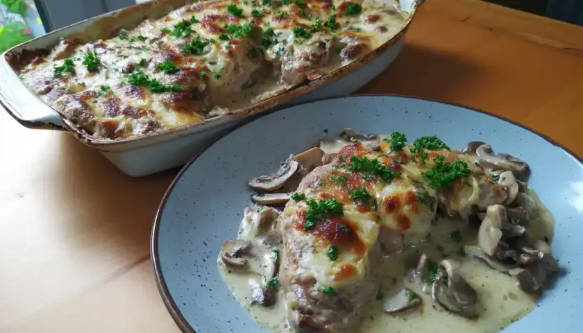 En krämig grekisk pyttipanna med svamp och gratinerad ost, toppad med persilja. Serveras i en ugnsform och på en tallrik.