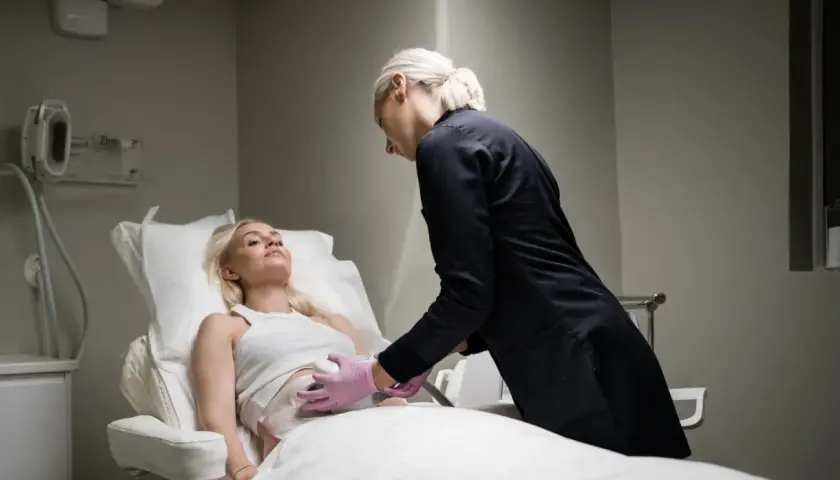 En kvinna får behandling för coolsculpting armar. En terapeut applicerar apparaten på hennes överarm.
