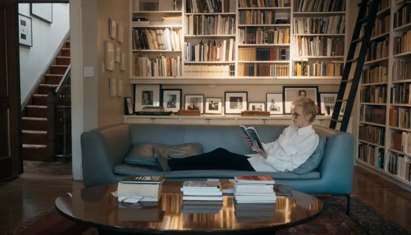 Siri Hustvedt, jung und nachdenklich, liest auf einem Sofa vor einem Bücherregal.