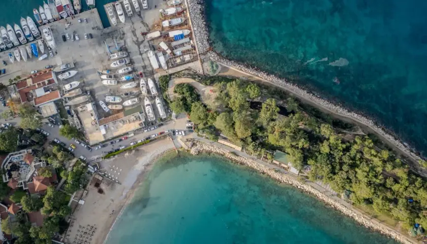 Widok z lotu ptaka na port i plażę w Kemerze, Turcja. Widać liczne jachty, łodzie, budynki i zielone tereny. To idealne miejsce na odkrywanie atrakcji Kemer.