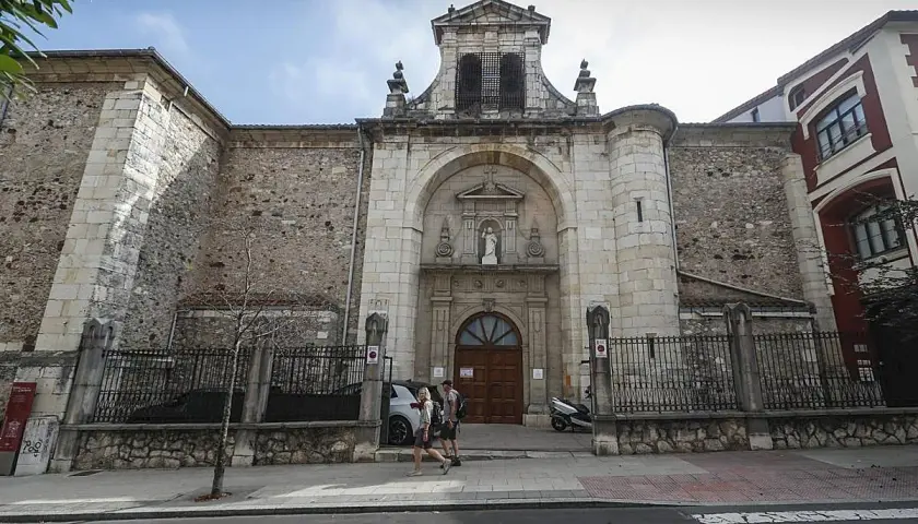 Fachada de la iglesia Consolación en Santander, con una pareja paseando por la acera.