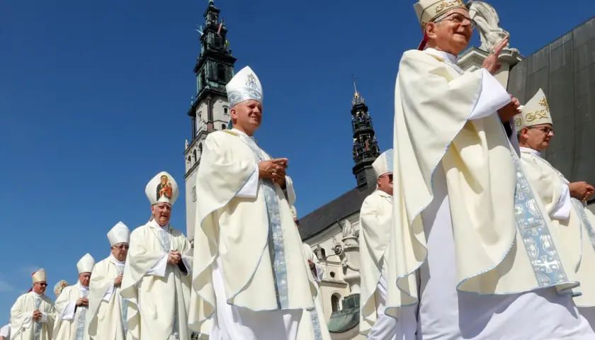 Biskupi w białych szatach procesyjnie idą pod jasnobłękitnym niebem. W tle widać wieże klasztoru, gdzie niedawno podpisano ważny konkordat.