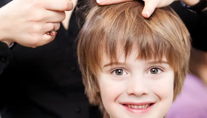 Un niño sonriente recibe unos cortes de pelo modernos.