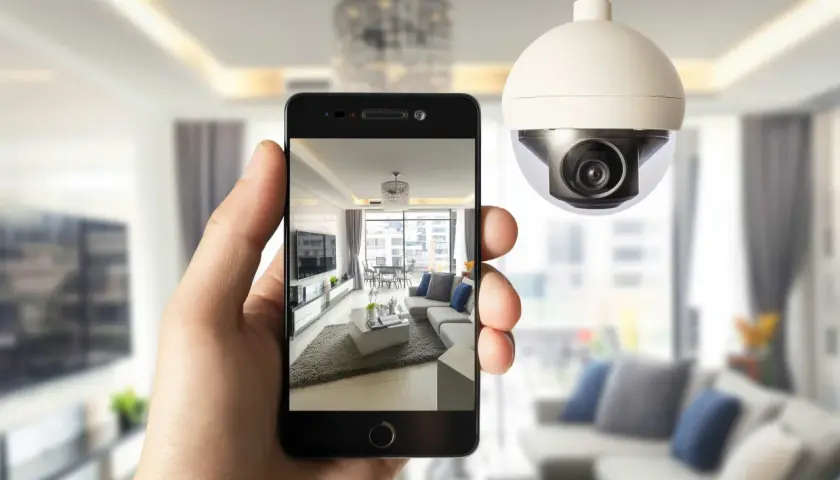 Una mano sostiene un teléfono que muestra una sala de estar moderna, mientras una cámara de seguridad wdr vigila el espacio.