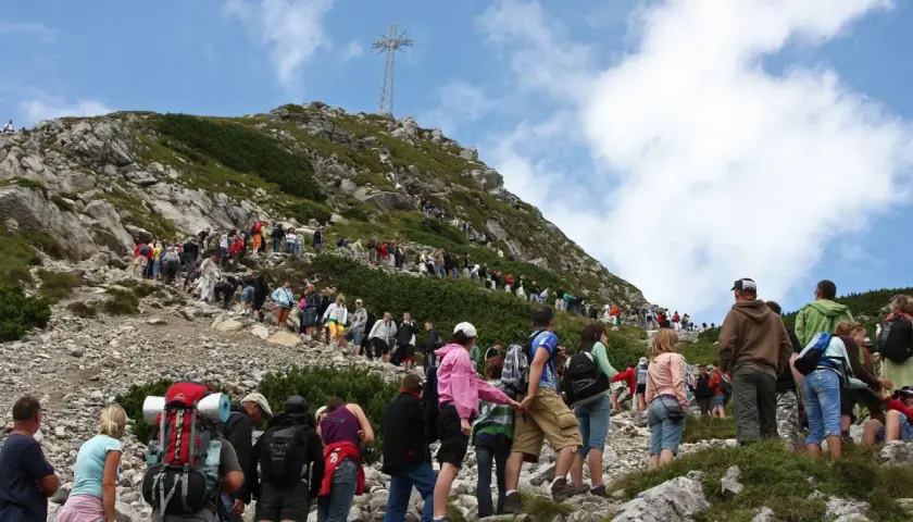 Tłum turystów na skalistej trasie na Giewont. W oddali widoczny krzyż.