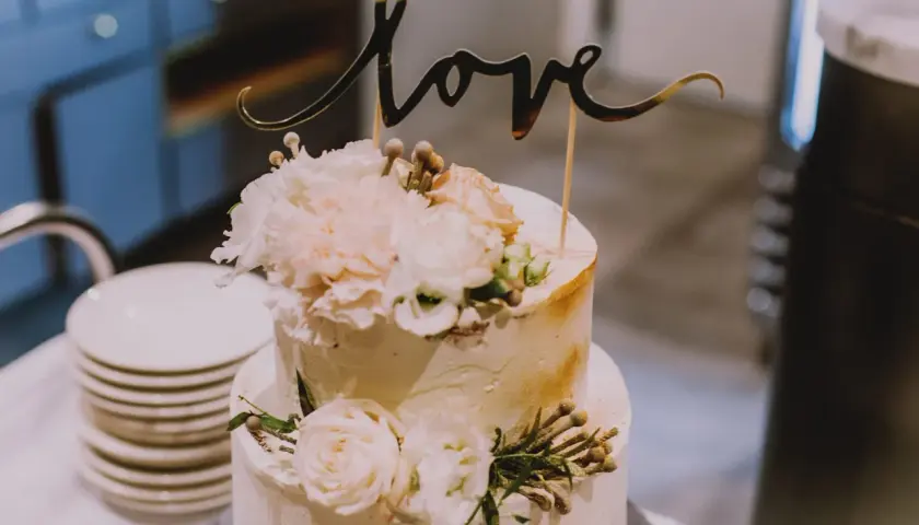 Elegancki tort weselny z napisem "love" i kwiatami. Wyobraź sobie jego pyszne tort weselny smaki!