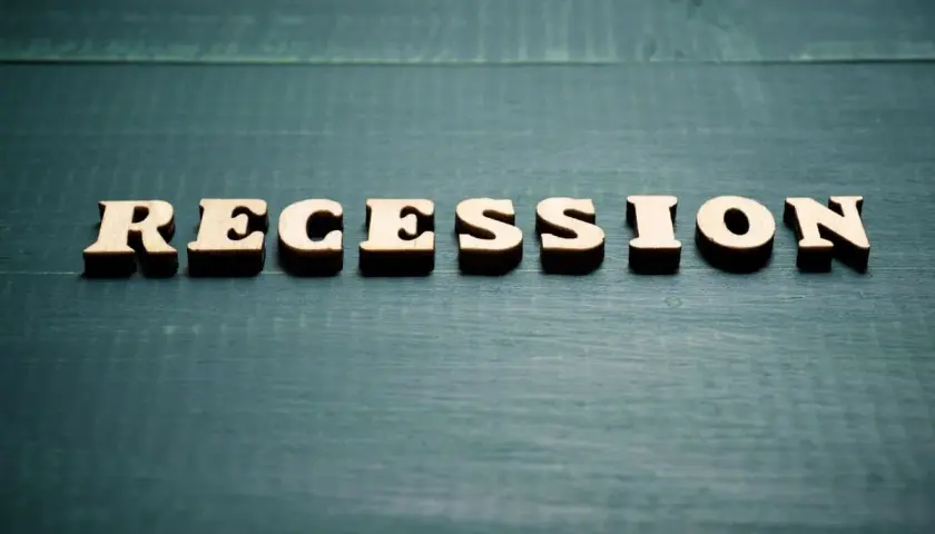 Drewniane litery układają słowo "RECESSION". To pojęcie ekonomiczne, które oznacza spadek aktywności gospodarczej.