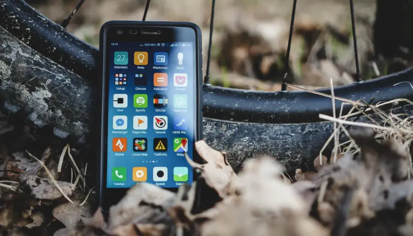 Szukasz alternatywy dla Endomondo za darmo? Smartfon z aplikacjami do śledzenia aktywności, jak Strava czy Locus Map, leży obok opony rowerowej.